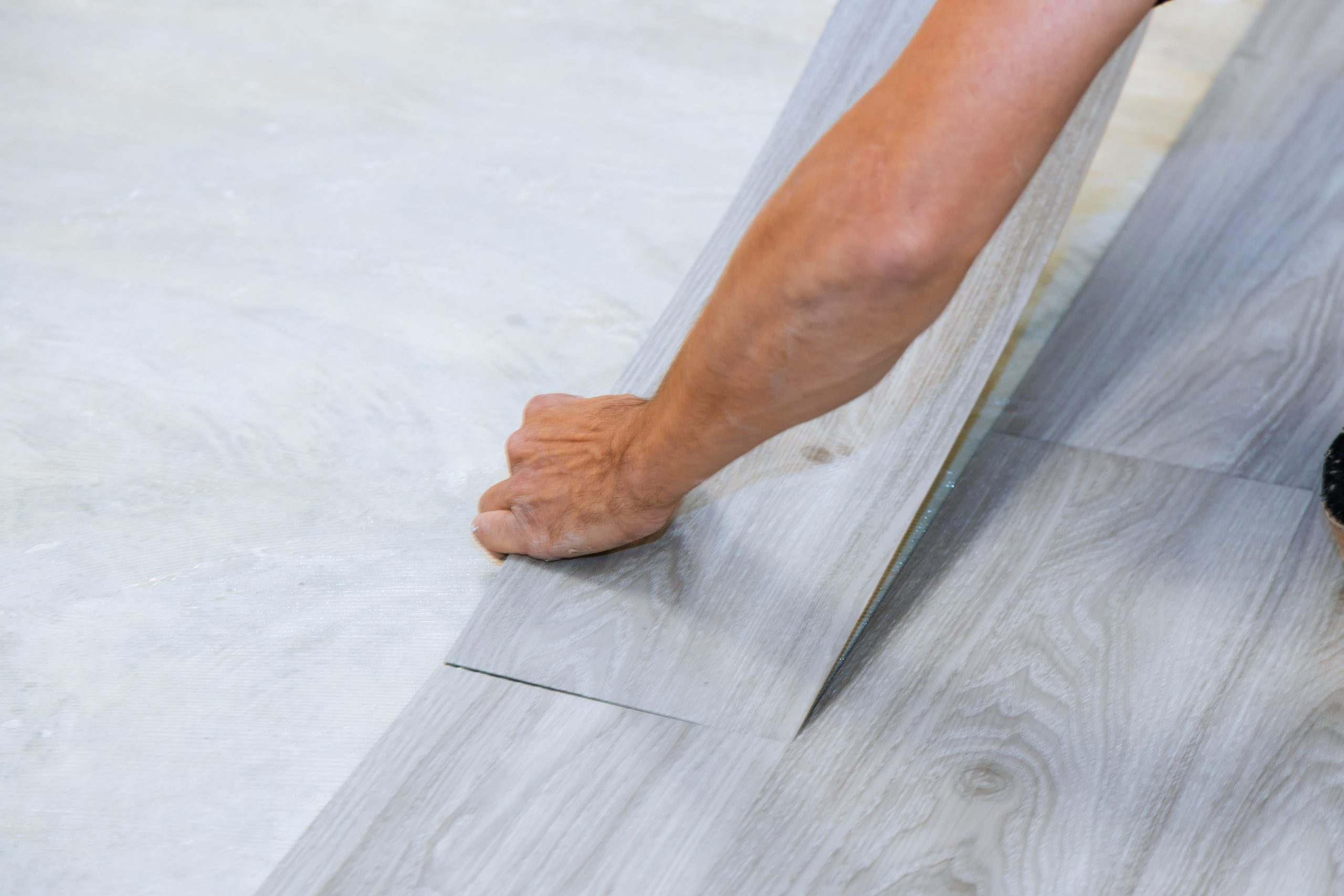 Worker installing new vinyl tile floor laminate wood texture floor with new home improvement